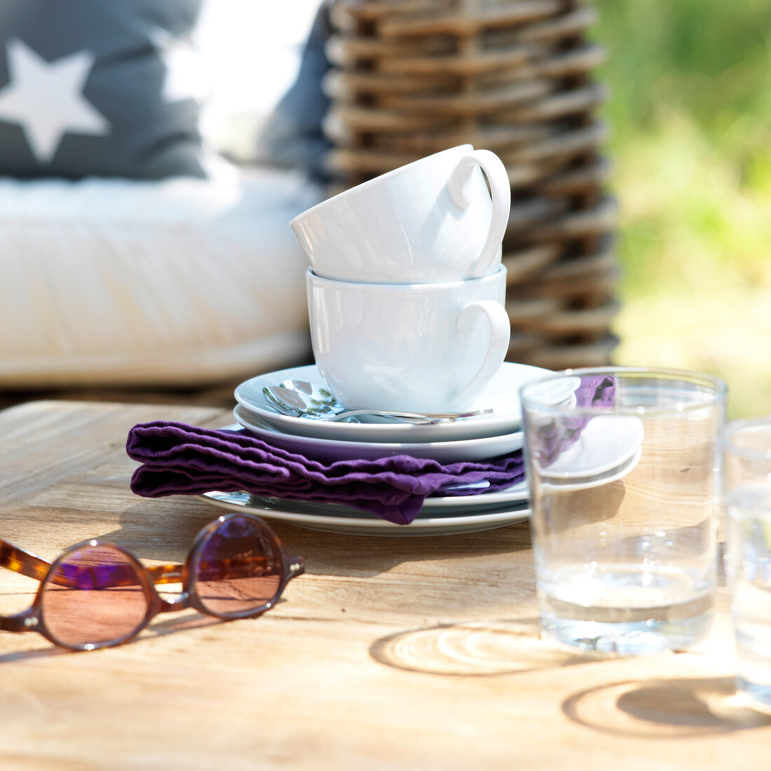 Dishes, glass, purple napkin and sunglasses on wooden surface