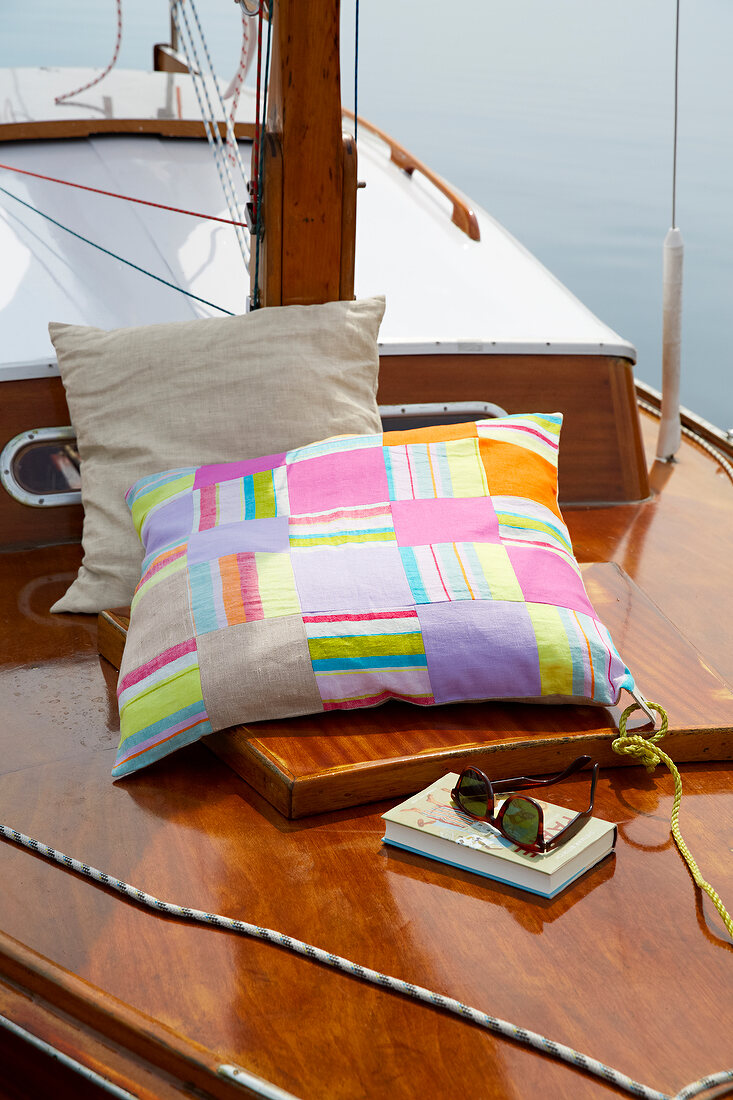 Two linen cushions on deck with sunglasses and book on side