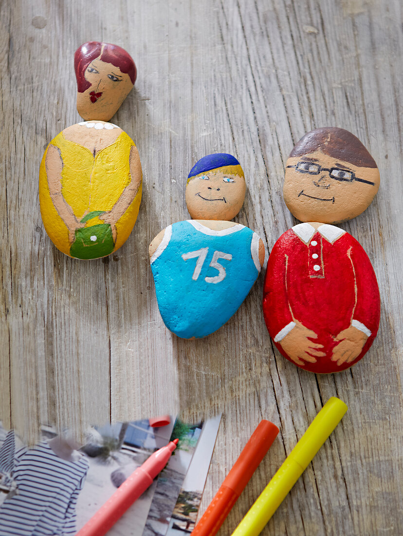 Painted stones in form of human figures on wooden surface