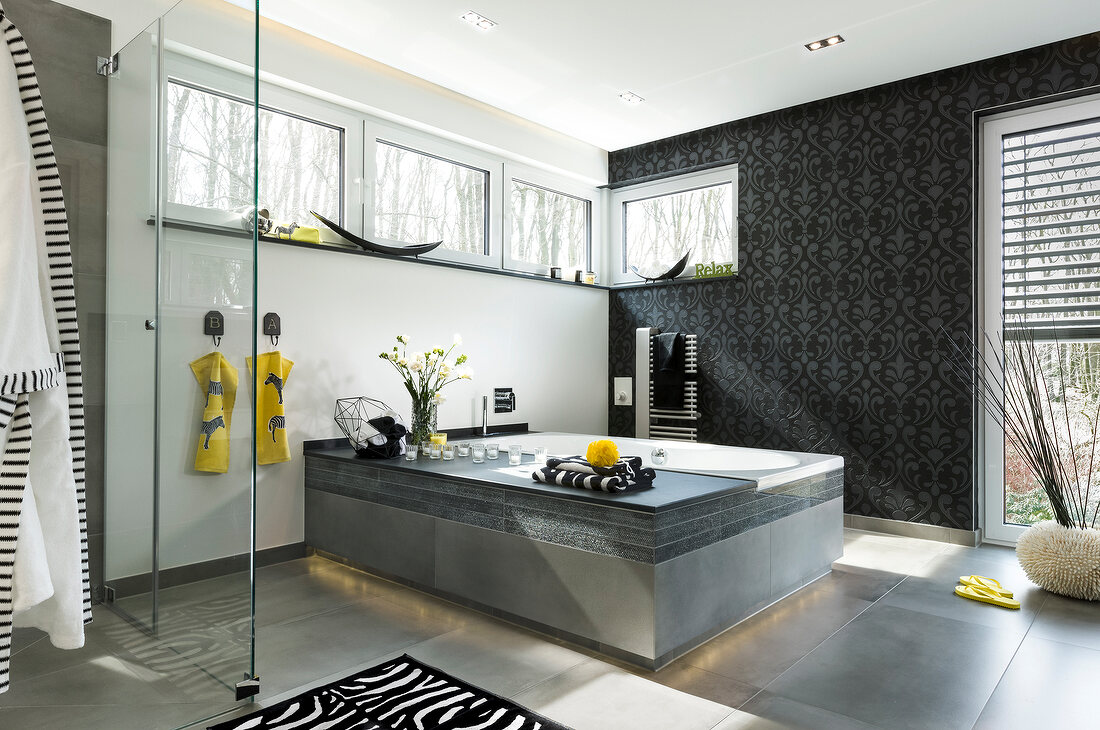 View of interior of elegant looking anthracite bathroom with luxury bath and resting bench
