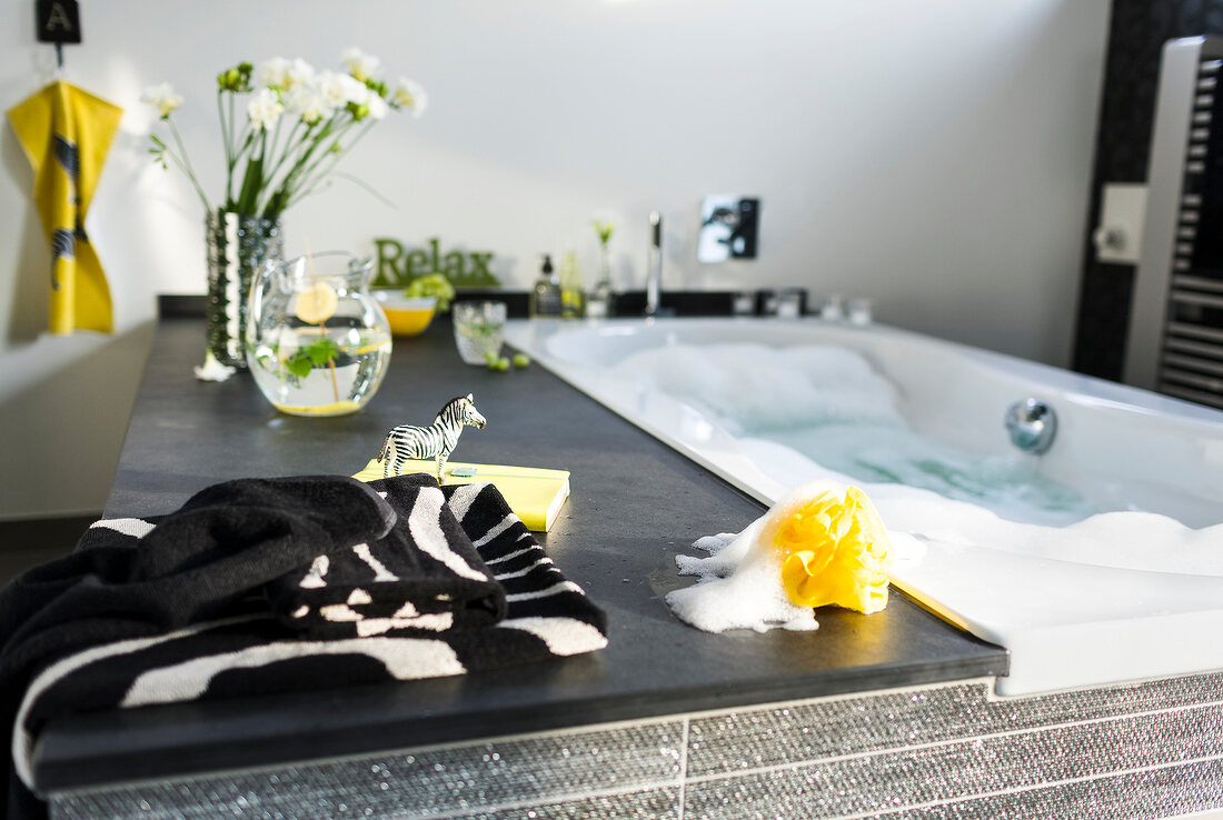 View of elegant looking anthracite bathroom with yellow sponge and towel near bathtub