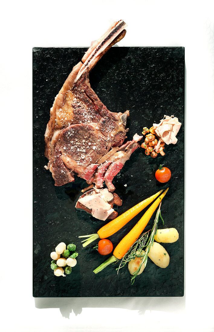Tomahawk steak with vegetables on plate
