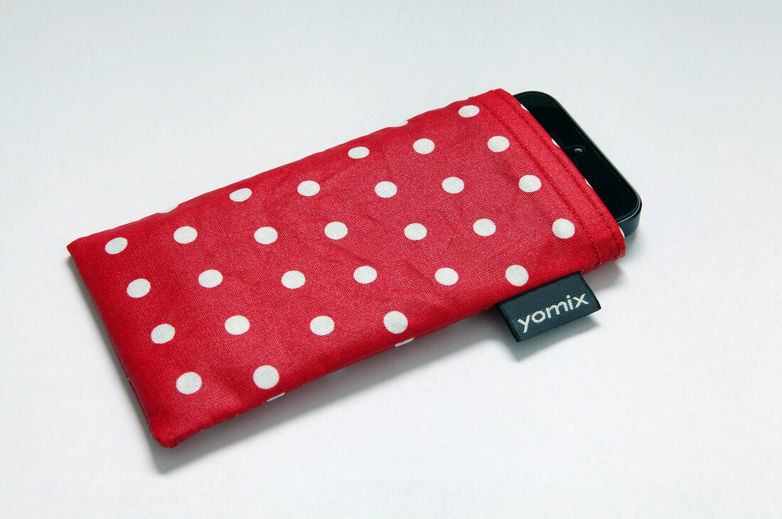 Close-up of red mobile phone case with white dots on white background