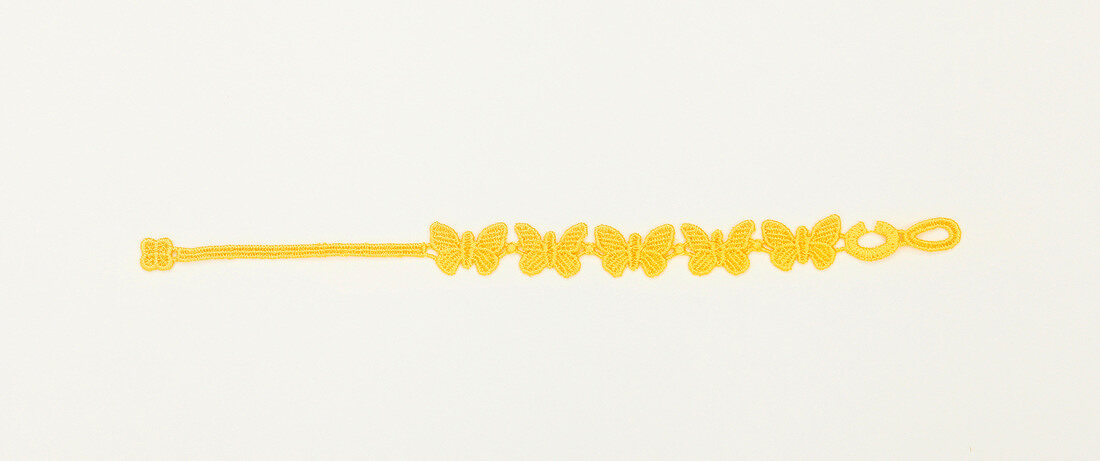 Close-up of yellow friendship bracelet with small butterflies on white background