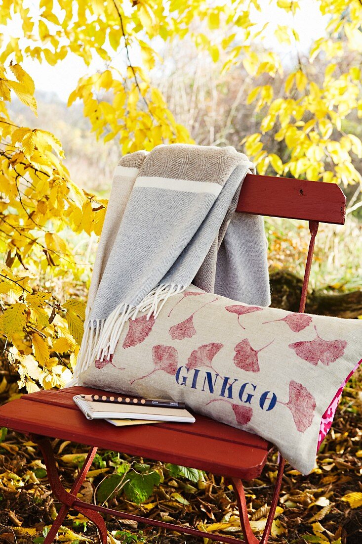 Printed linen cushion on folding chair in autumnal garden