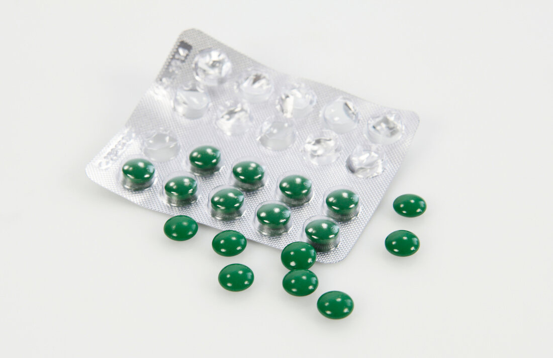 Green shiny pills packs with pills on background