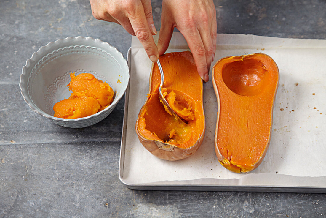 Pumpkin flesh being scooped out with spoon