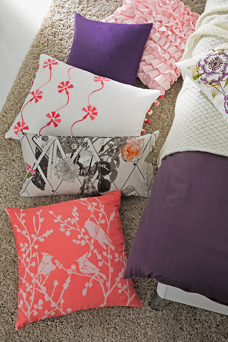 Various colourful and patterned pillows on floor