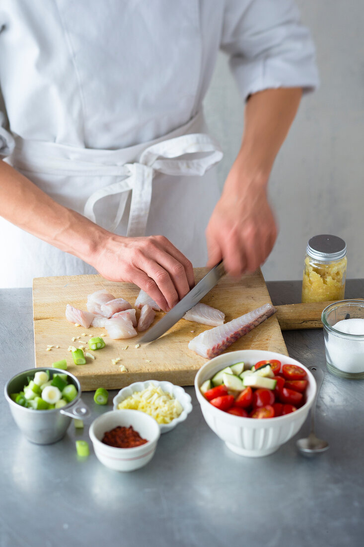 Close-up of chef cutting raw fish on chopping board