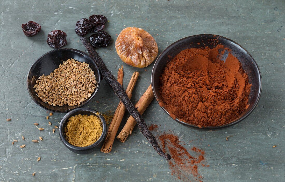 An arrangement of cocoa powder, cinnamon, vanilla pods, dried fruit and anise