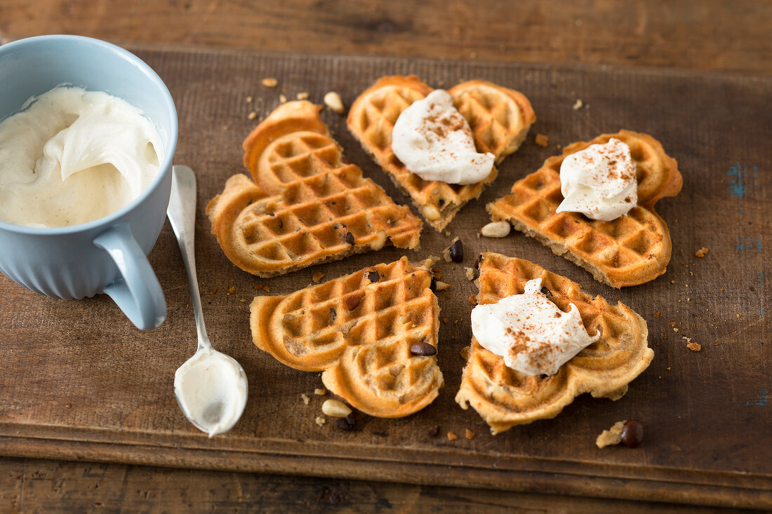 Heart shaped espresso waffles with pine nuts on wooden board