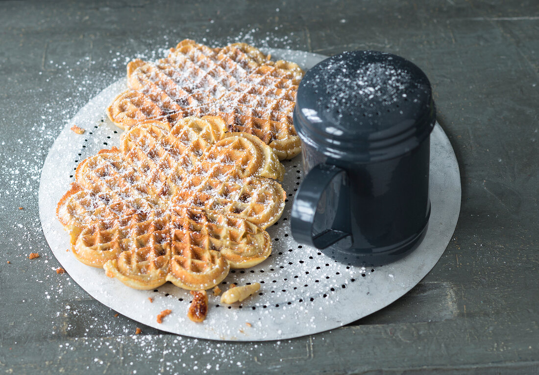 Fig waffle with icing sugar and icing sugar shaker on cake rack