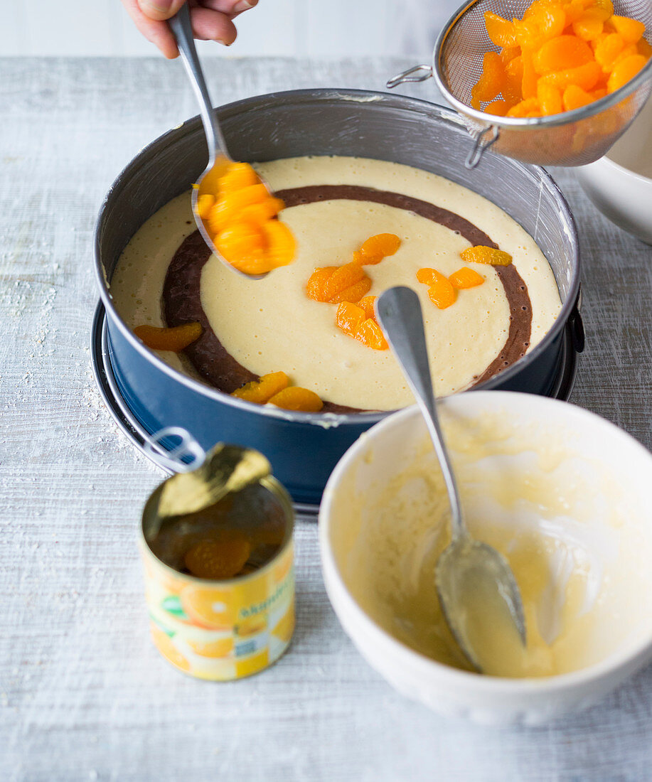 Mandarin marble cake being made – mandarins being scattered on top of the cake mix