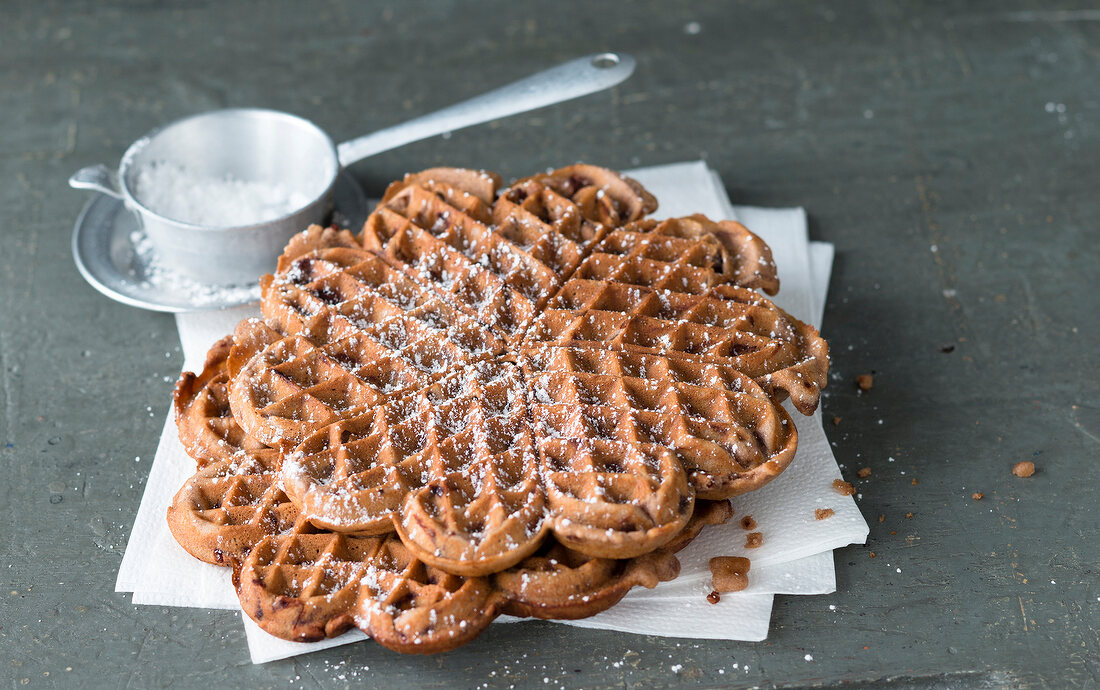 Chocolate waffles with icing sugar in sieve 