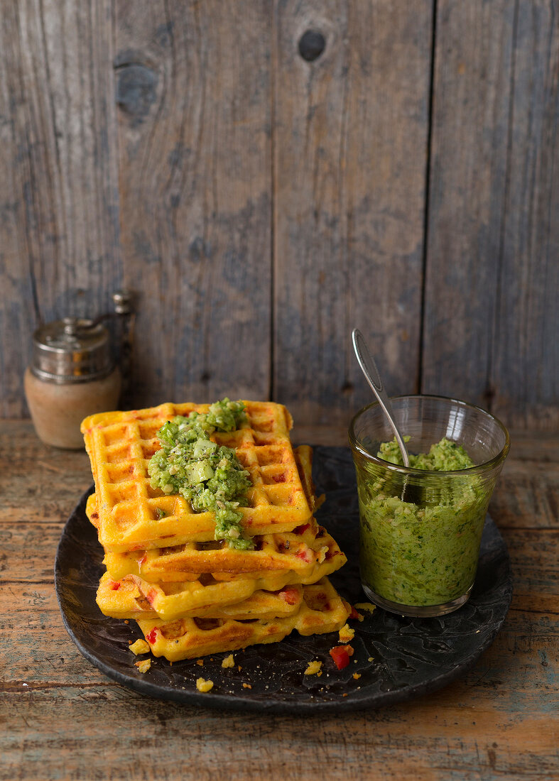 Stack of polenta waffles with fennel cream and pesto on plate