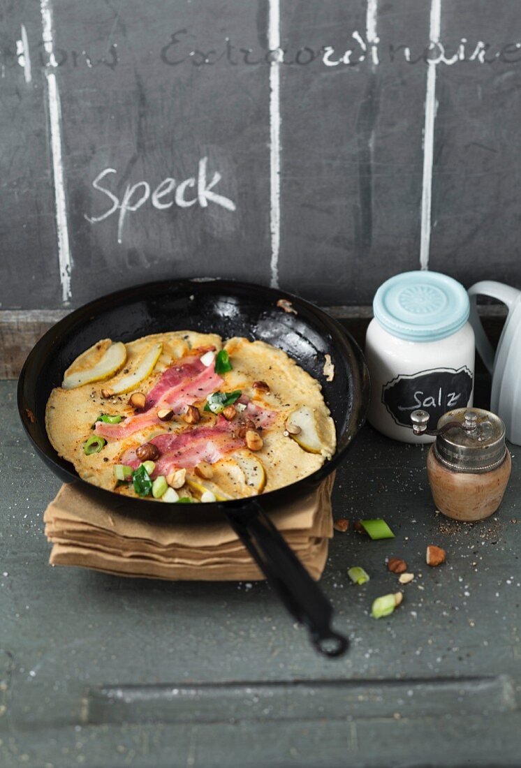 Bacon pancakes with pears and hazelnuts in a pan