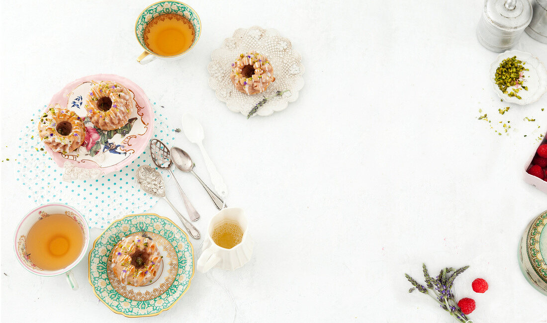 Mini bundt cakes on plates with tea cups on white background