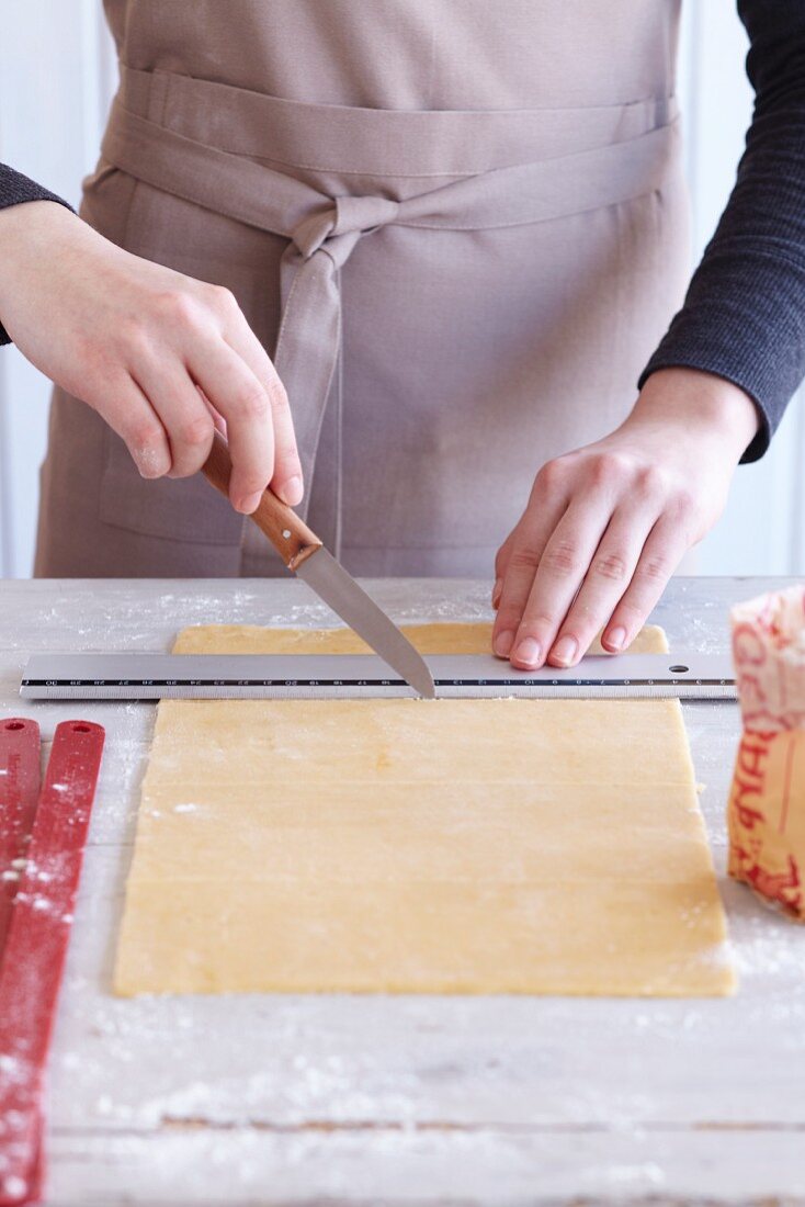 Zebra biscuits being made: rolled out pastry being cut into strips