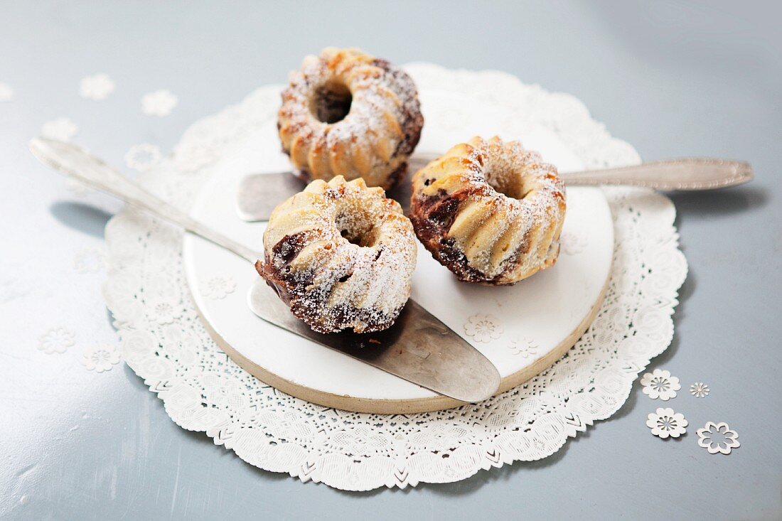 Mini marble Bundt cakes with icing sugar on a plate with a cake slice
