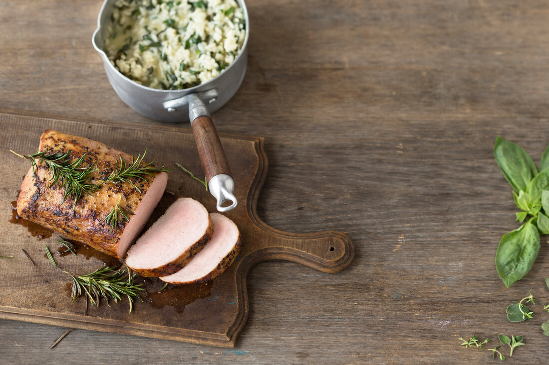 Roasted pork with risotto and rosemary on chopping board