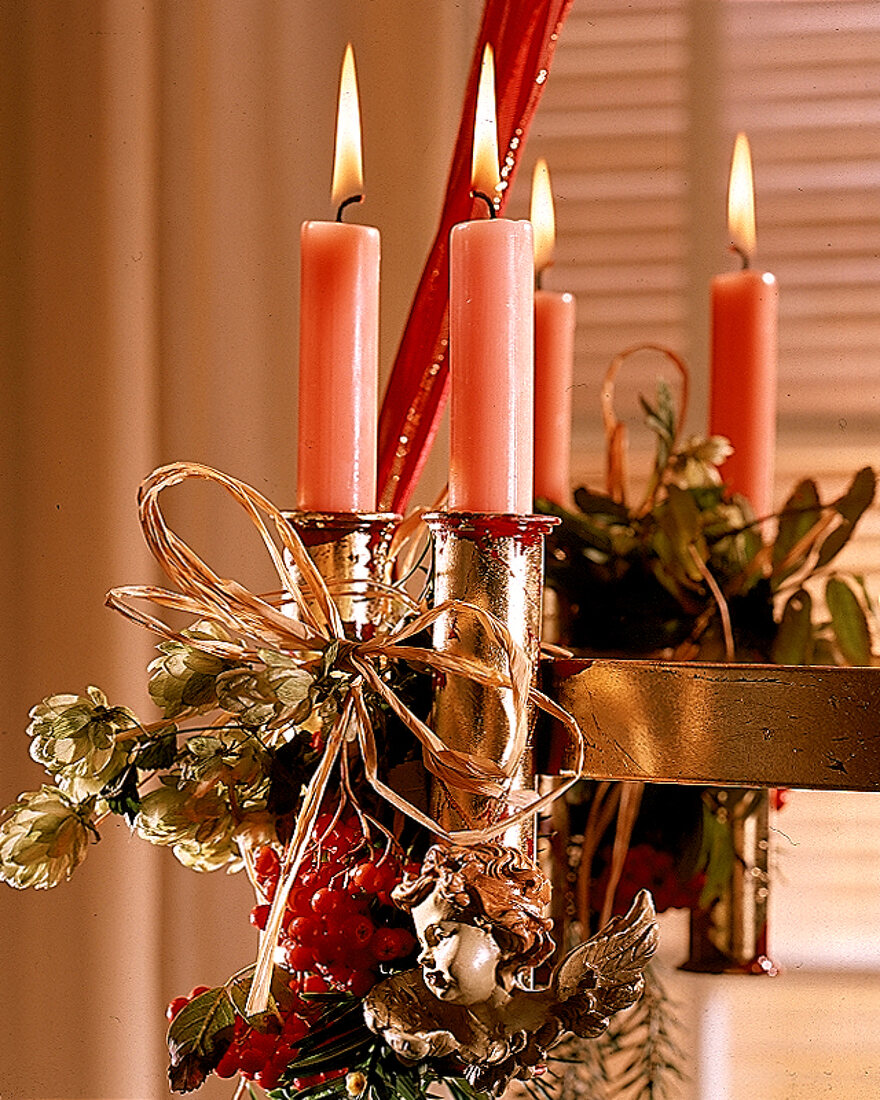 Rosa Kerzen am Leuchter, mit Engelkopf und roten Beeren