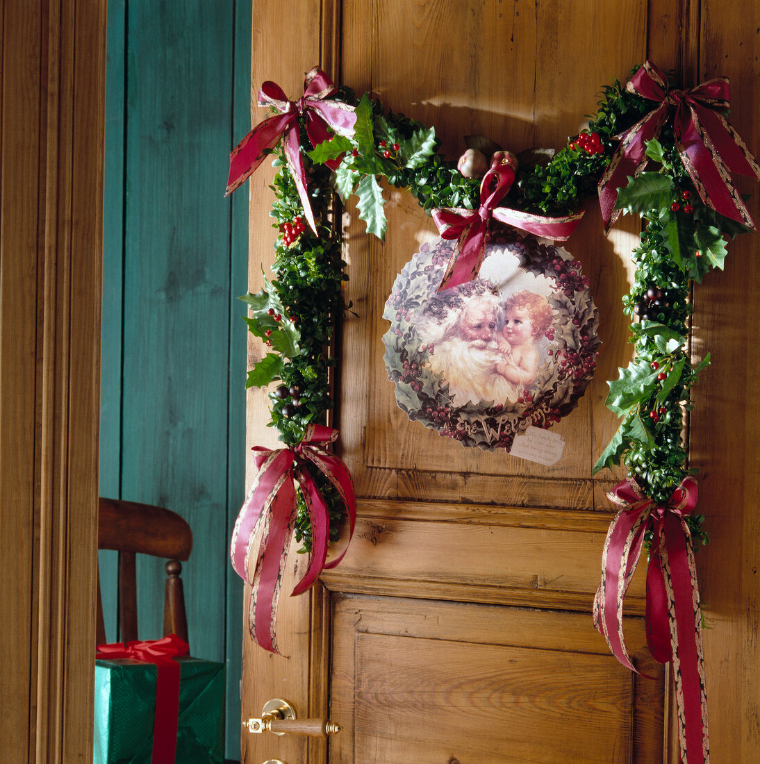 Holly berry leaves garland with picture of Santa Claus hanging on wooden door