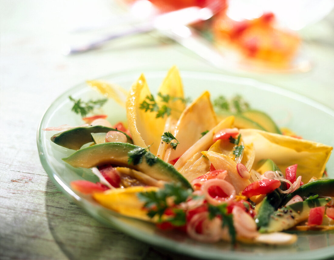 Chicory salad with avocado, tomatoes and walnuts on glass plate