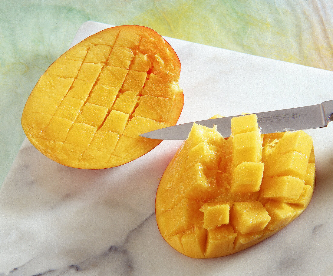 Halbierte Mango mit teilweise herausgelöstem Fruchtfleisch