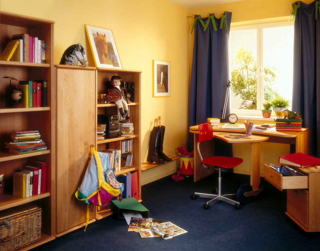 Children's room with study desk near window and comics books on ground