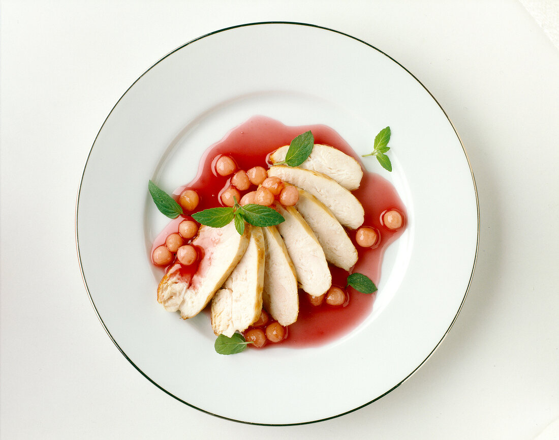 Chicken breast with redcurrant sauce served on plate, overhead view