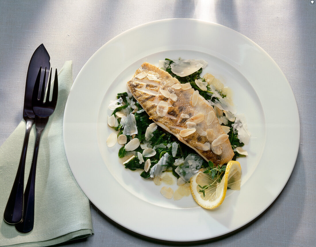 Zander fillet garnish with spinach and almonds on plate