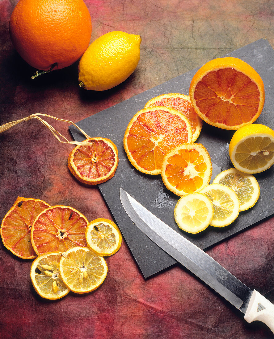 Whole and sliced oranges and lemon on chopping board