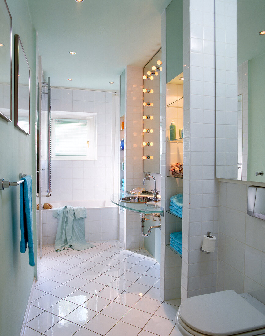 Interiors of tiled bathroom with turquoise coloured towels