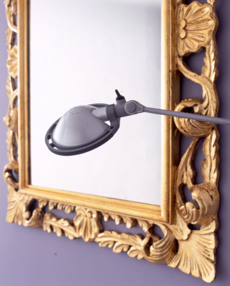 Detail: schnörkeliger Spiegel mit Goldrahmen