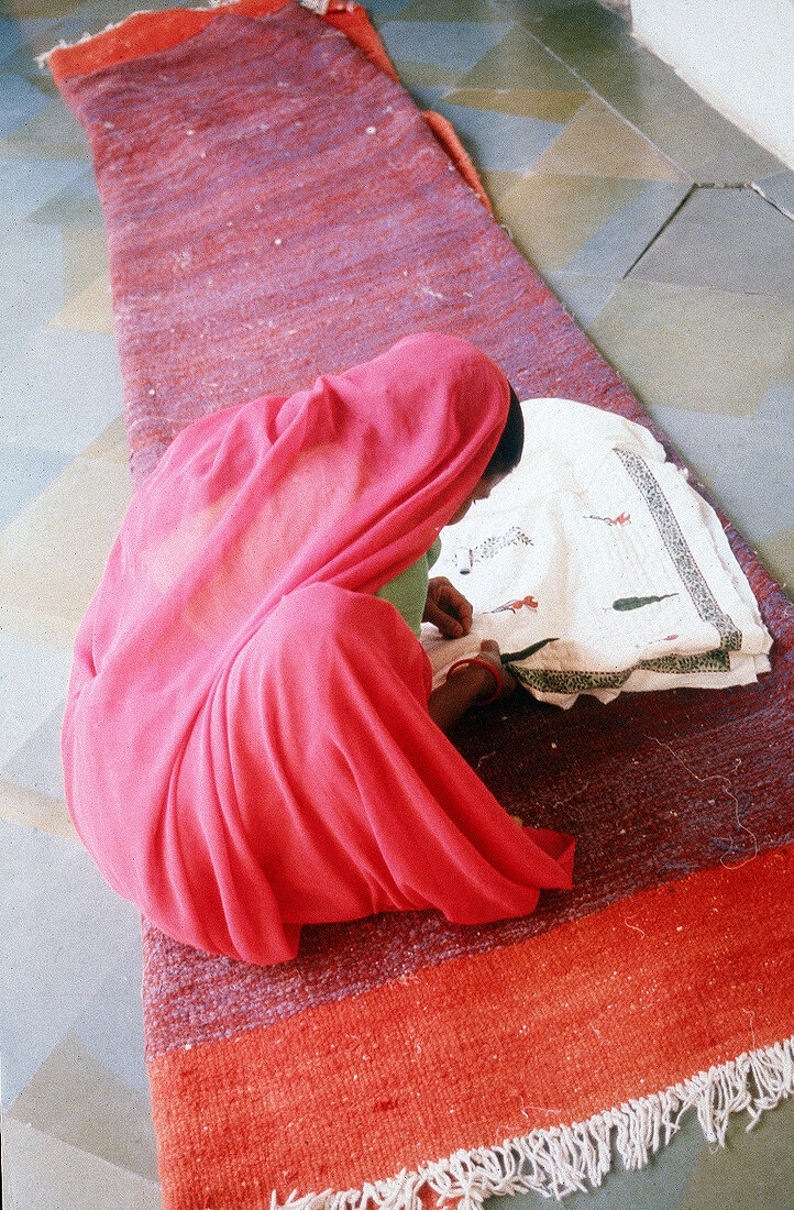 Inderin im rosa Sari bestickt eine Decke