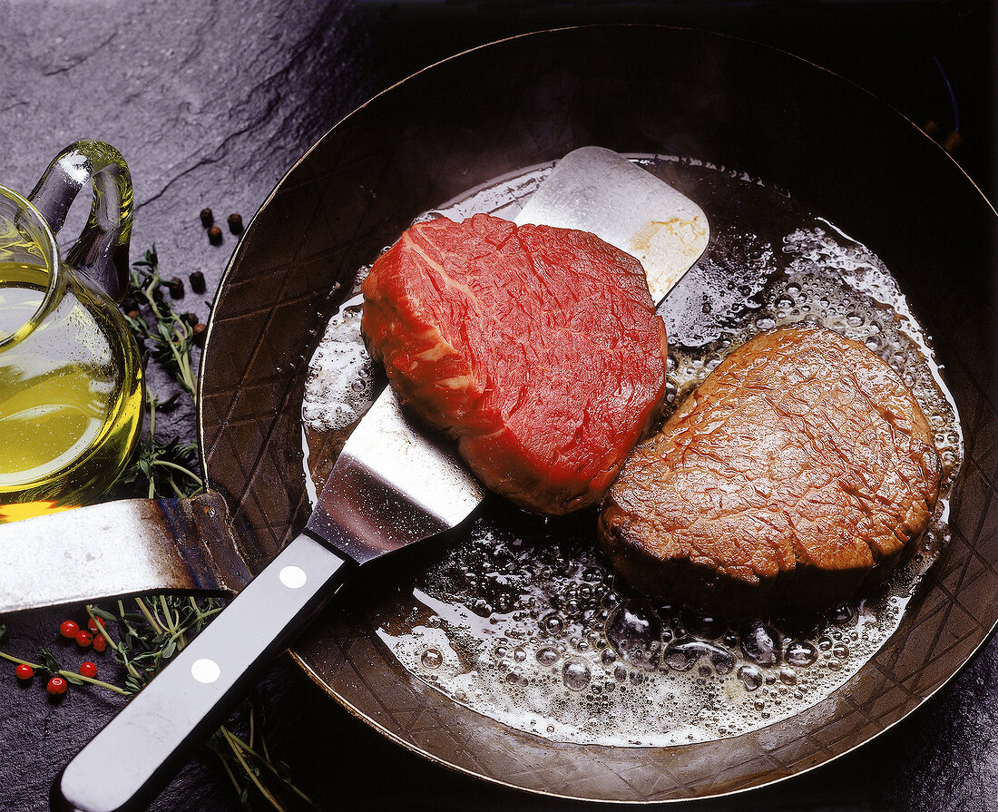 Zwei Steaks werden in einer Pfanne gebraten
