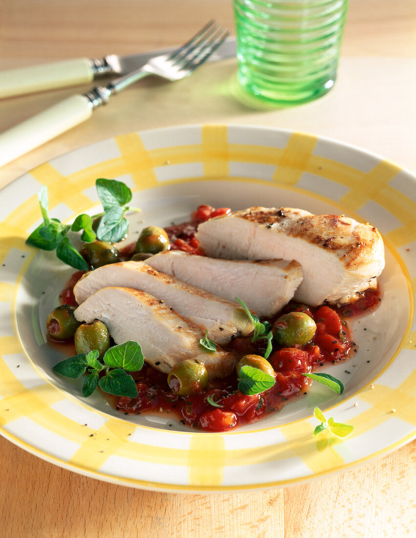 Chicken breast with tomato olive sauce on plate