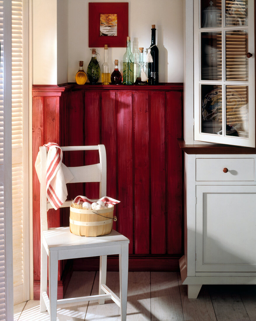 Wood panelled kitchen with red wall and white painted furniture