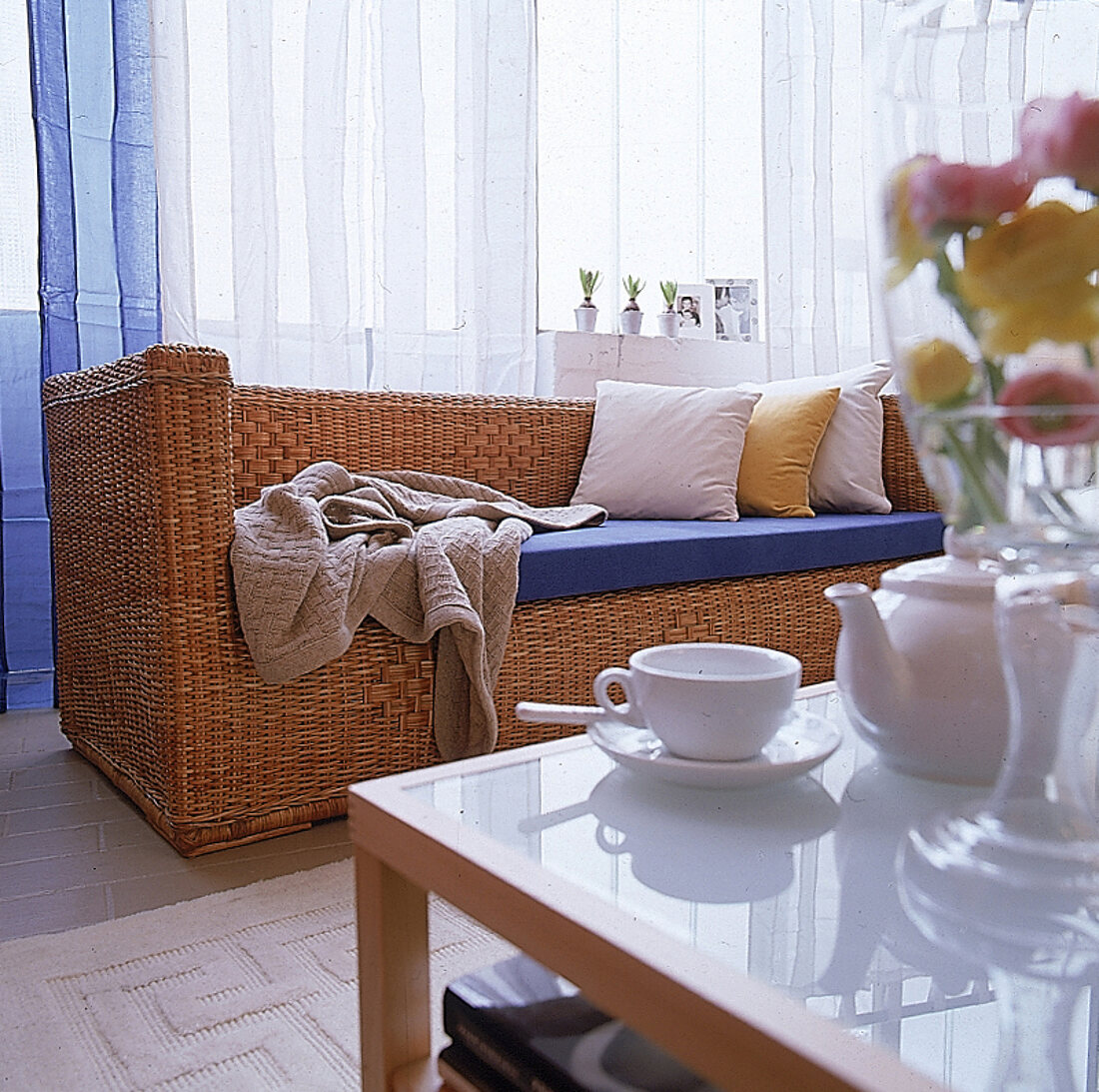 Honigfarbenes Rattansofa mit blauer Stoffsitzfläche