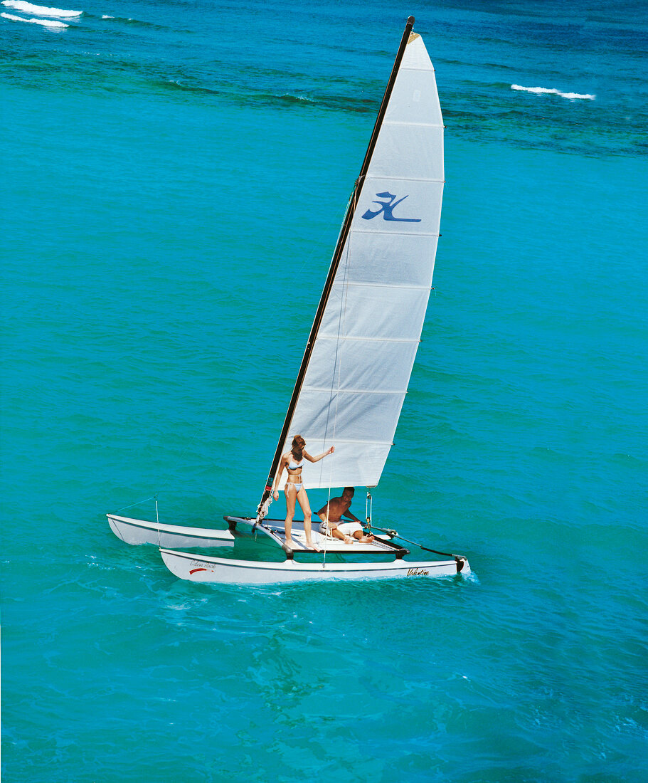 Paar segelt mit weißem Katamaran auf türkisblauem Meer