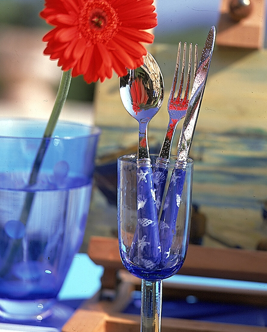 Besteck mit blauen Griffen und Muschelmotiven in Weinglas
