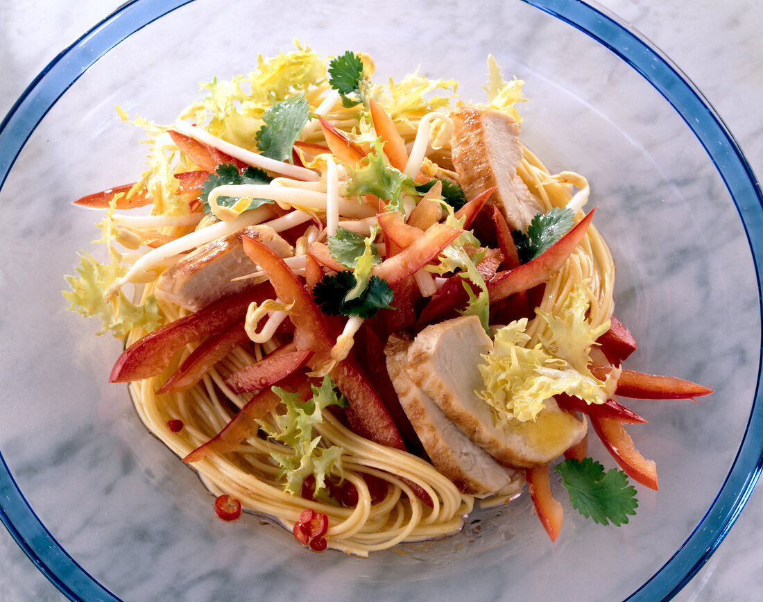 Close-up of frisee salad with chicken breast and red pepper