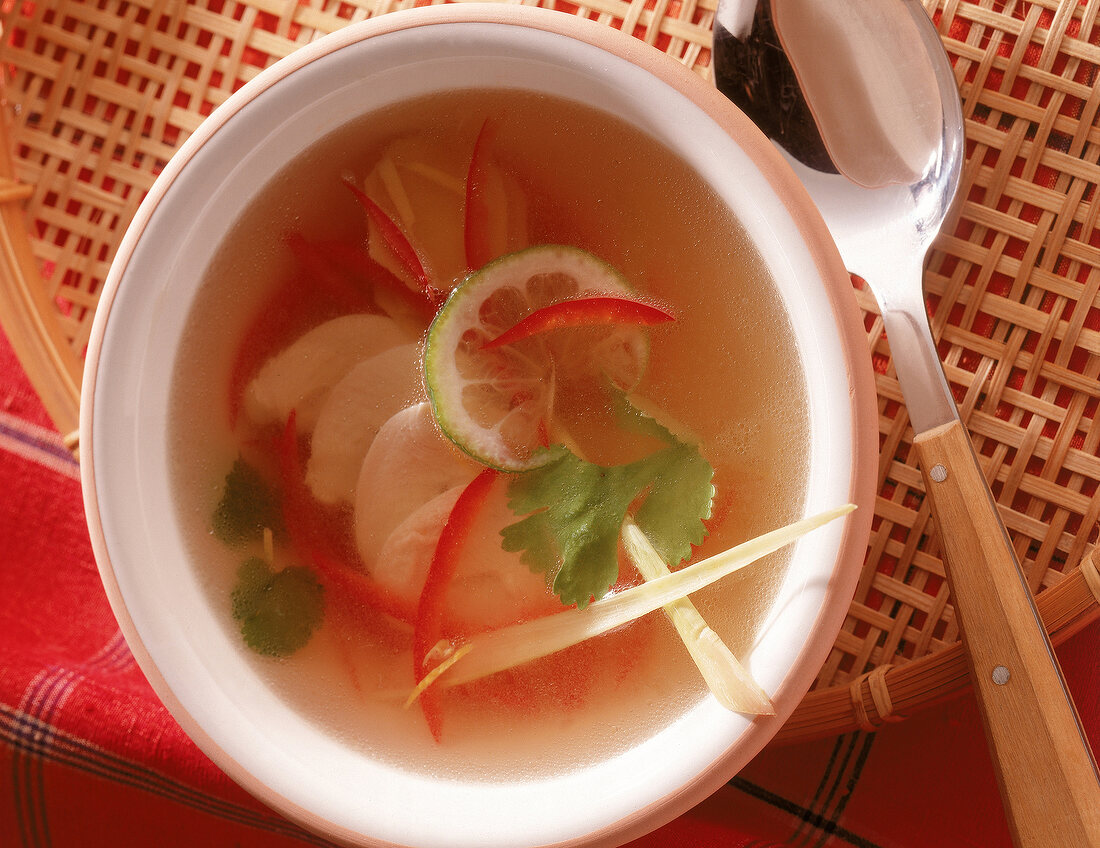 Thailändische Hühnersuppe mit Limettenscheibe und Korianderblatt