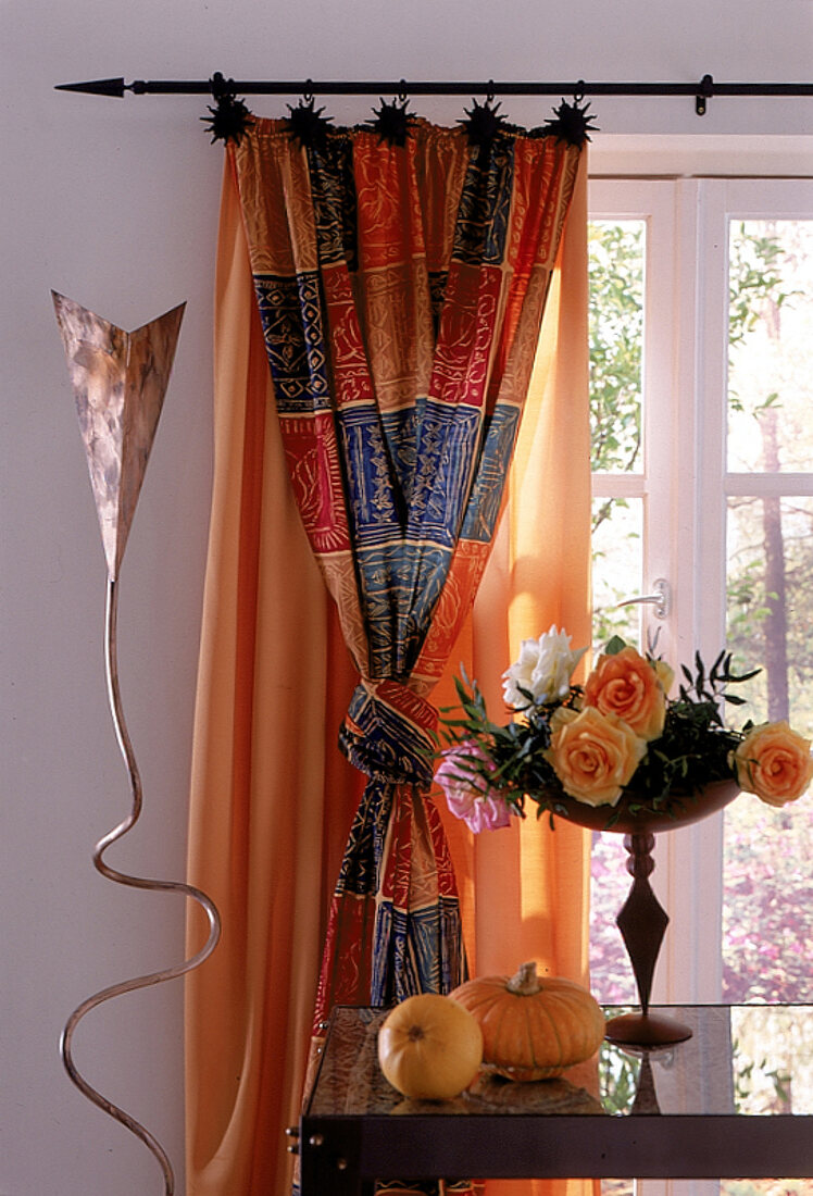 Hohes Fenster mit langem, bunten Baumwollvorhang, geknotet