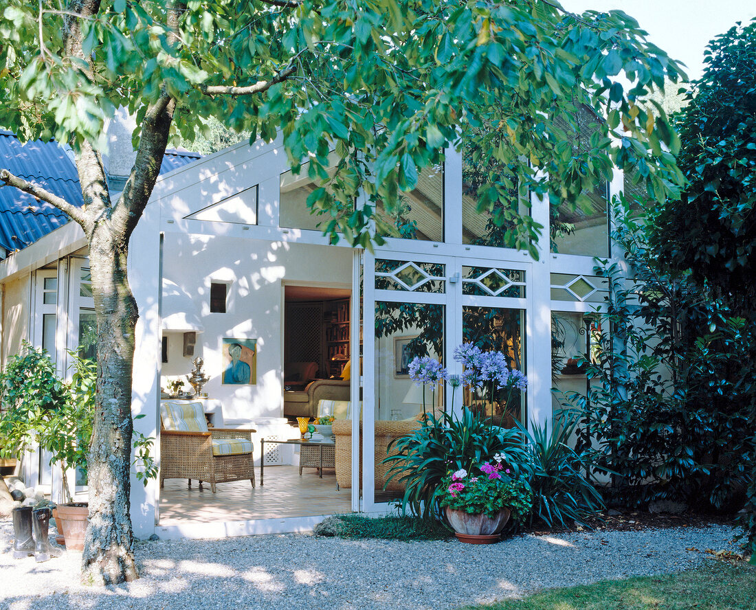 Exterior of conservatory house with potted plants and tree