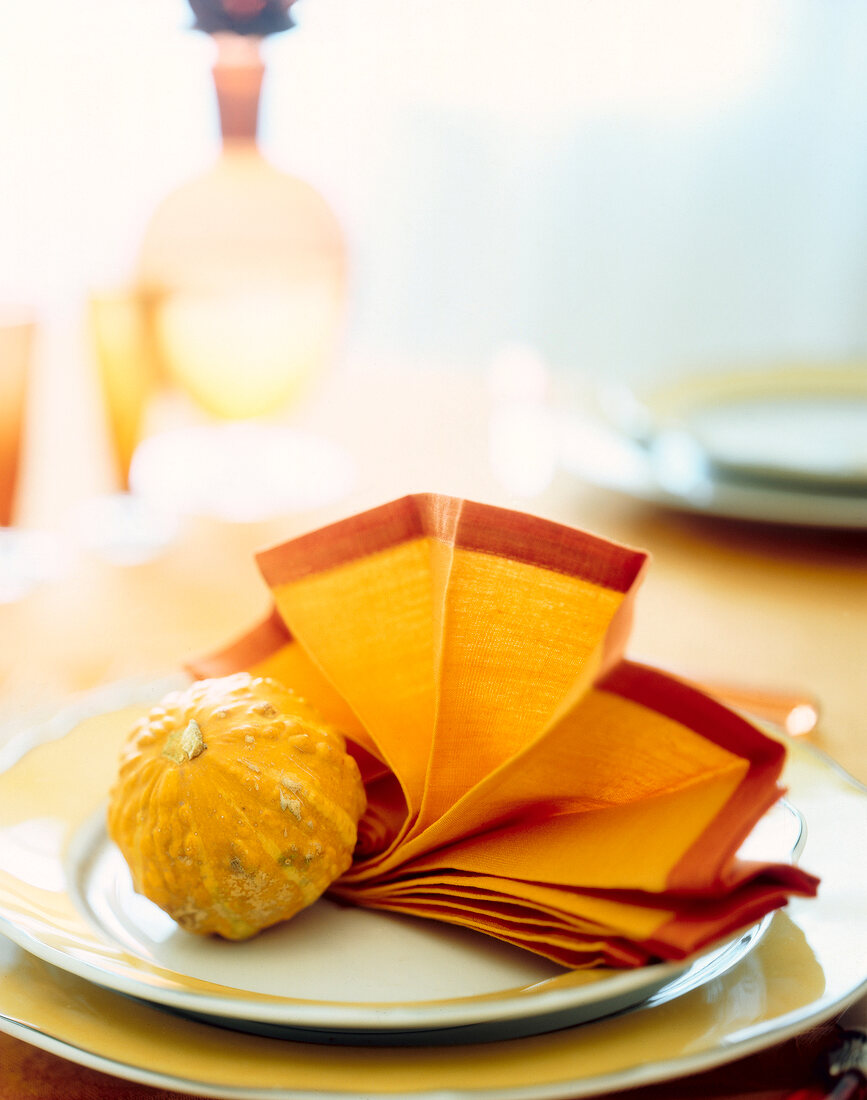 Plate with small pumpkin and orange fanned napkin