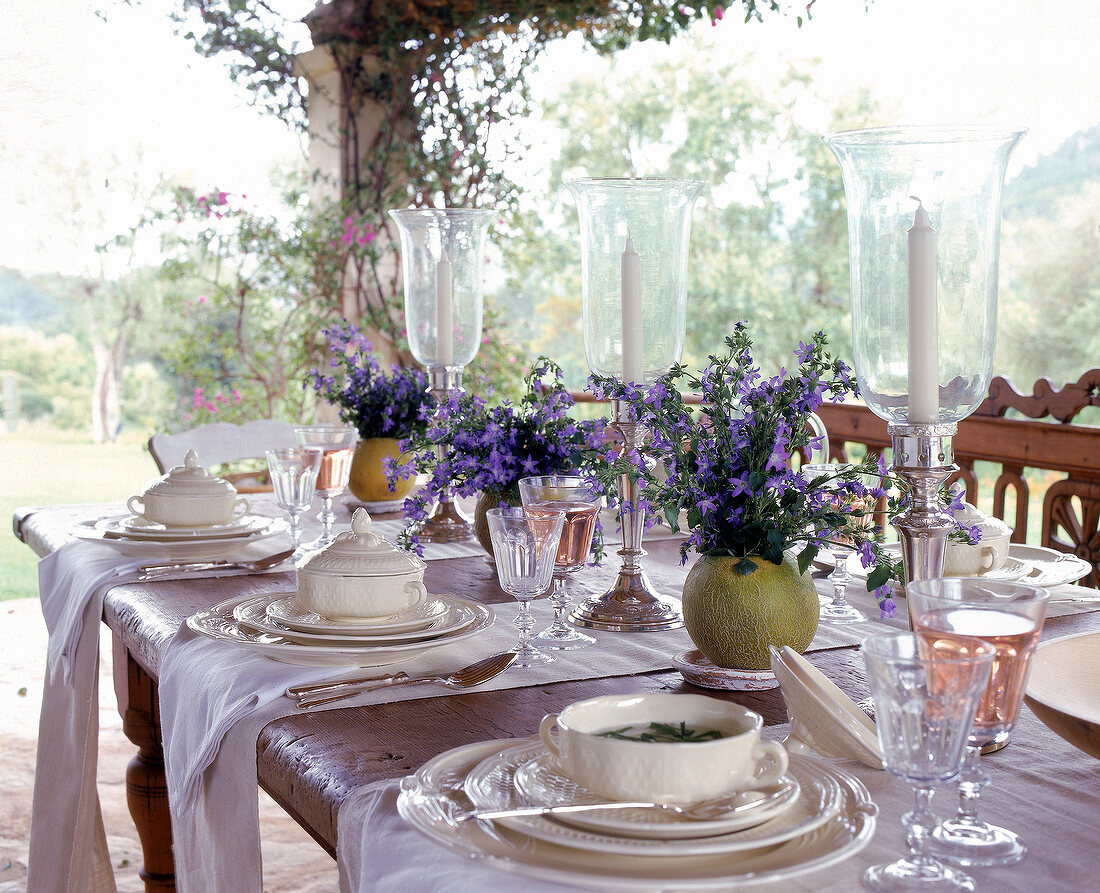 festlich gedeckter Tisch im Freien Campanula-Blüten in Melonen-Vasen