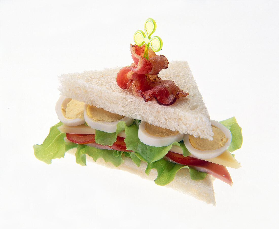 Club sandwich with egg, ham, tomatoes and salad on white background