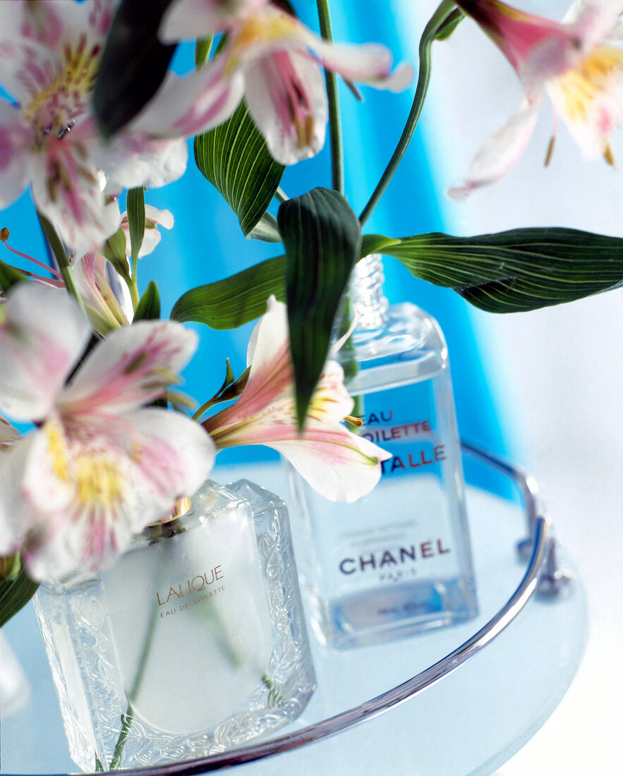 Close-up of two perfume bottles with flowers in it