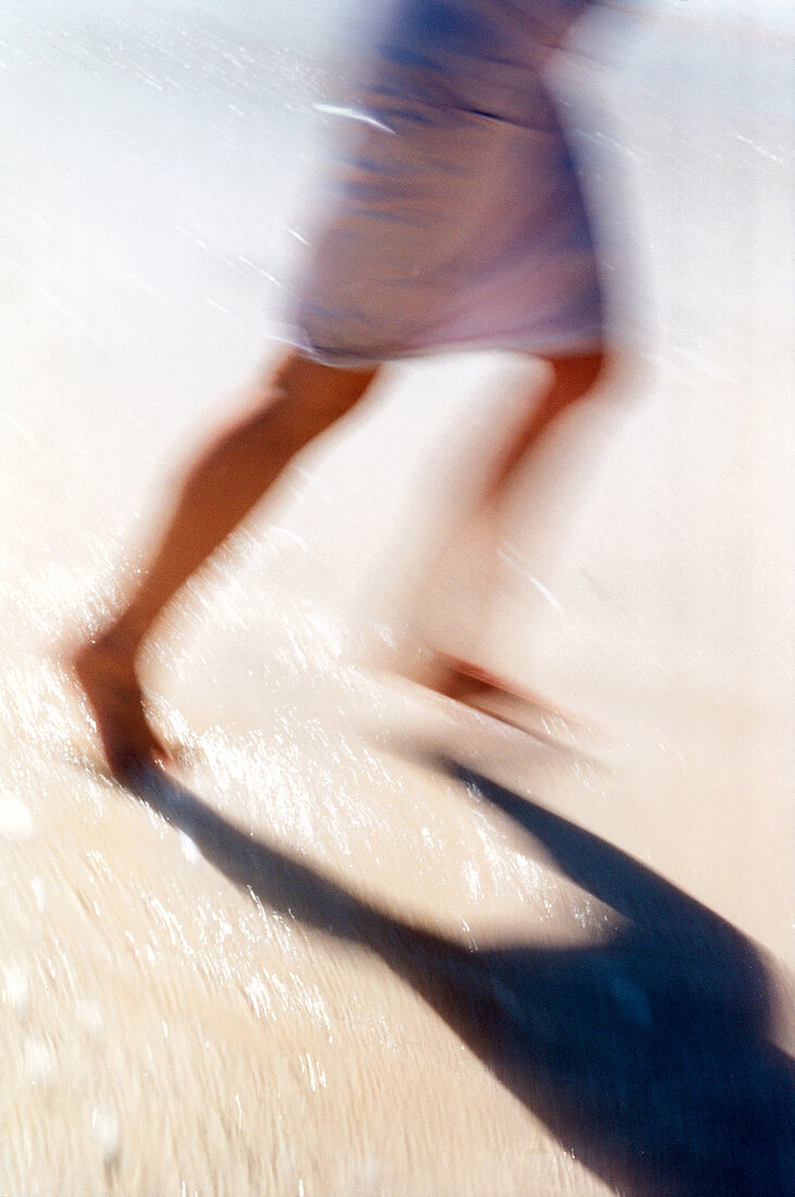 Frauenbeine in Bewegungsunschärfe laufen am Strand